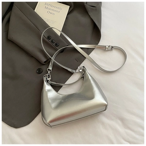 Sac hobo croissant argenté brillant avec bandoulière réglable sur tissu blanc