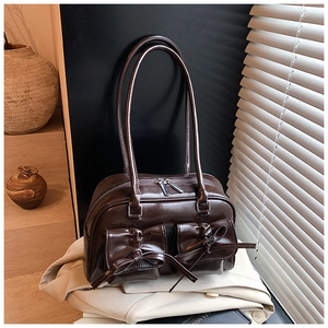 Detailed view of brown retro leather shoulder bag with decorative bows and twin pockets