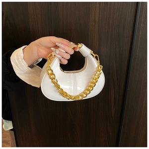 Detail of white glossy leather mini dumpling bag with chunky gold chain handle