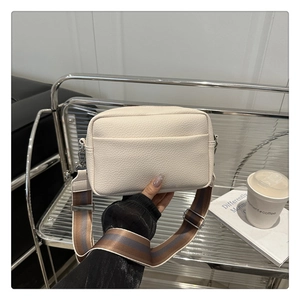 Detail of off-white lychee texture leather crossbody bag with striped canvas strap