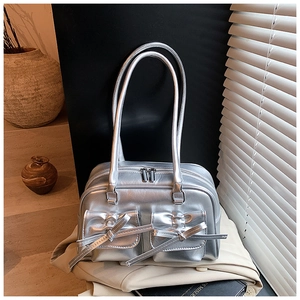 Detail of silver metallic shoulder bag with front double pockets and chic bow ties