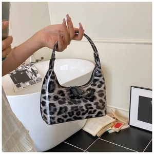 Detail view of the glossy patent leather leopard print handbag with zip closure