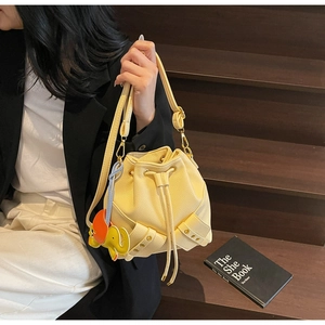 Detail of light yellow leather bucket bag with drawstring and elephant charm on stairs