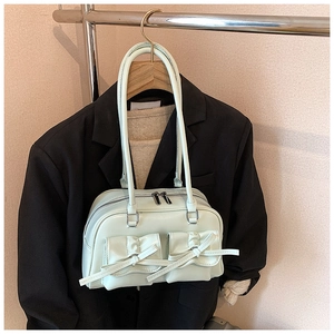 Detail of light green bowling bag with decorative bow pockets and silver metal zippers