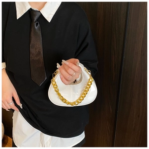 Close-up of white mini dumpling bag with glossy patent finish and thick gold chain strap