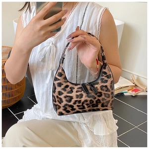 Detail of glossy leopard print crescent bag with dual zippers and chain handle