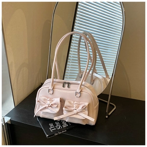 Close-up of pale pink glossy bowling bag featuring bow detail and silver metal zippers