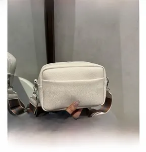 Detail of white lychee grain leather crossbody bag with a colorful striped wide strap