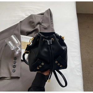 Detail of black pebbled leather bucket bag with gold hardware and drawstring closure