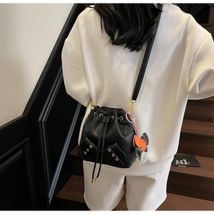 Detail of black drawstring bucket bag with litchi grain leather and animal charm