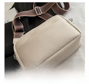 Close-up of cream PU leather crossbody bag with lychee texture and striped woven strap