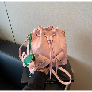 Close-up of pink bucket bag with drawstring, lychee texture and leaf pendant detail