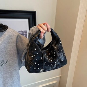 Black crescent bag with sparkling rhinestones and a single handle held by a model