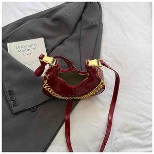Detail of red patent leather mini dumpling bag with gold chain and metal buckle