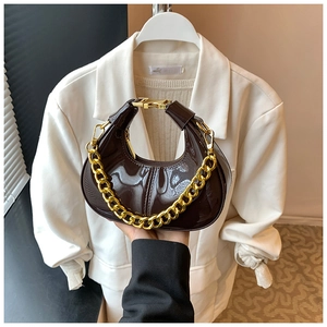 Detailed view of glossy dark brown crescent bag with decorative chunky gold chain