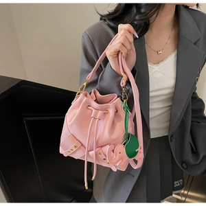 Detailed view of pink drawstring bucket bag with litchi grain leather and elephant charm