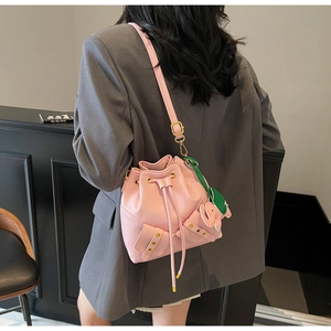 Detailed shot of pink drawstring bucket bag with gold hardware and elephant charm