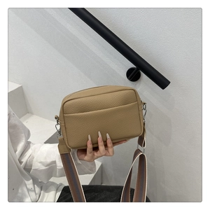 Close-up of brown litchi textured cross body bag with colorful striped wide strap
