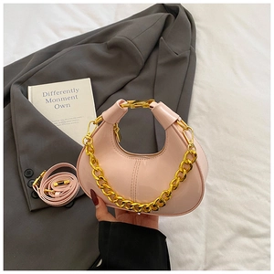 Detail view of pink patent leather dumpling bag with chunky gold chain and shoulder strap