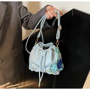 Detail of light blue pebble leather bucket bag featuring a cute elephant charm and gold studs