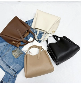 Detailed flat lay of textured leather bucket bags with gold rings and knot handles