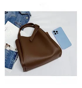 Brown lychee grain leather handbag detail showing capacity for iPad mini and phone