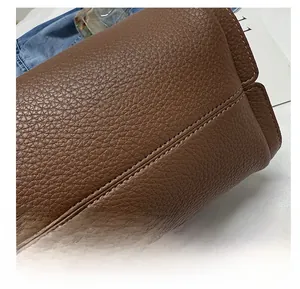 Detail of neat sewing technology and lychee texture on dark brown leather handbag
