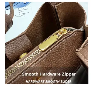 Close-up of smooth gold-tone metal zipper on high-quality brown pebble leather handbag