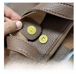 Detail of brown litchi leather bag featuring dual strong magnetic clasps and gold zipper