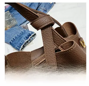 Close-up of deep brown lychee leather handbag with decorative strap and gold hardware