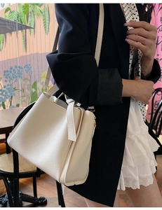 Detail of off-white lychee grain leather bucket bag with elegant gold metal hardware