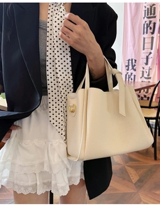 Close-up of off-white lychee pattern leather tote bag with golden D-ring hardware