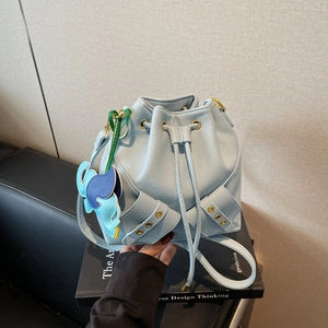Light blue drawstring bucket bag with litchi grain leather and a colorful elephant charm