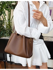 Detailed view of dark brown pebbled leather texture on bucket bag with gold metal buckle