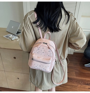 Detailed back view of a pink quilted mini backpack worn by a model in a modern office setup