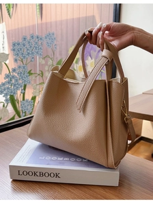 Detailed view of beige pebbled leather tote bag with gold hardware and hand carry handle