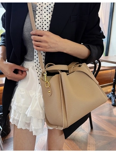 Detail of khaki pebbled leather bucket bag with gold-tone hardware and decorative knot