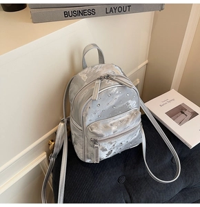 Close-up of a silver mini backpack with sparkling rhinestones and double zipper detail