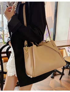 Detailed side view of beige leather satchel with gold hardware and shoulder strap