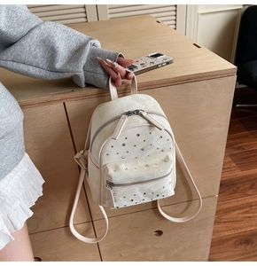 Detail of cream quilted mini backpack featuring sparkling rhinestone accents and smooth finish