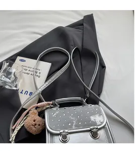 Close-up of silver crossbody bag with sparkling rhinestones and a plush bear charm