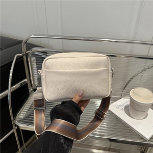 Chic beige lychee grain crossbody bag with a modern wide striped fabric shoulder strap
