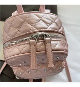 Detail of pink quilted mini backpack showing smooth silver dual metal zippers and rhinestones