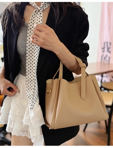Detail of beige pebble leather handbag with gold D-ring and elegant lifestyle styling
