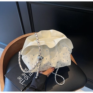 Detail of cream pleated cloud bag with sparkling rhinestones and silver chain strap