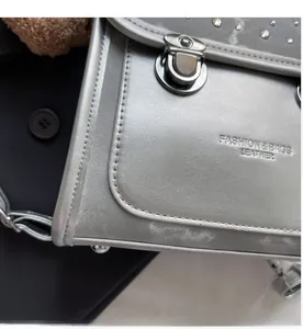 Detail of silver metallic flap bag featuring studded edges and secure metal buckle closure