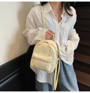 Close-up of pale yellow mini quilted backpack with silver rhinestones and front pocket