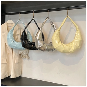 Détail de quatre sacs croissants plissés en bleu, noir, argent et beige sur un support