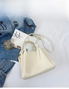 Close-up of off-white lychee grain leather handbag with gold metal hardware and strap
