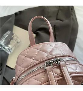 Detailed macro view of pink quilted leather bag with dual zippers and handle